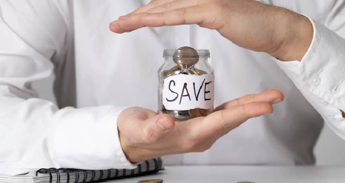 A person holding a jar labeled SAVE filled with coins, symbolizing the importance of saving money.