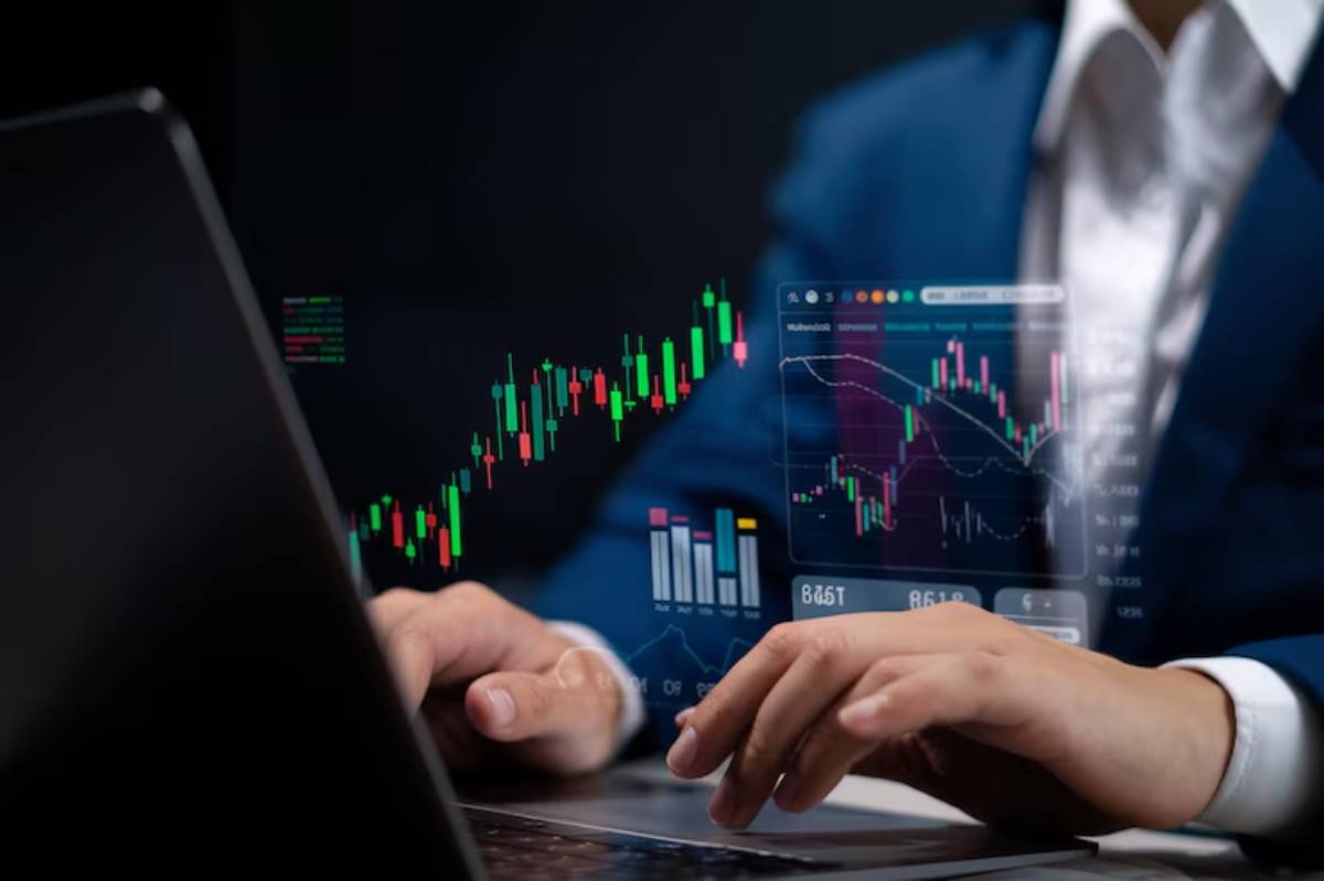 A business professional in a suit analyzes digital financial charts and data on a laptop, showcasing stock market trends.