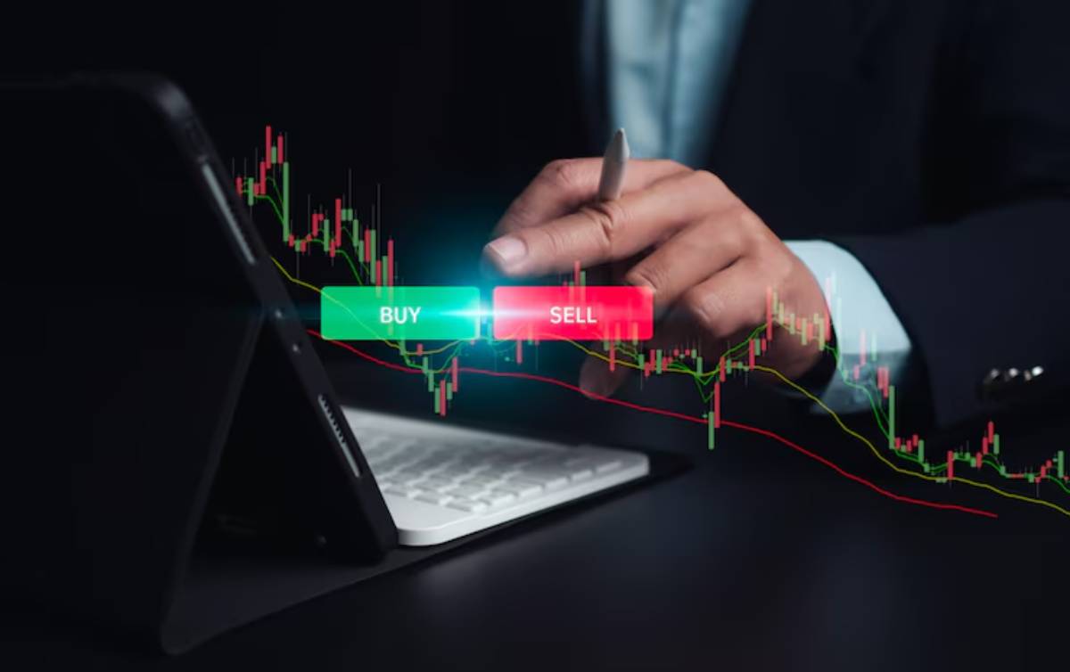 A trader's hand hovers over a tablet, with BUY and SELL buttons glowing beside a digital stock chart.